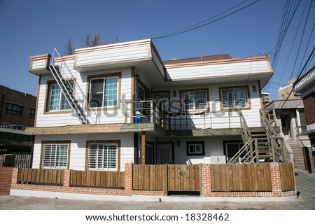 Comfortable Cozy White Painted Two Story House Surrounded by Low Wooden Fence Against Deep Blue Sky
