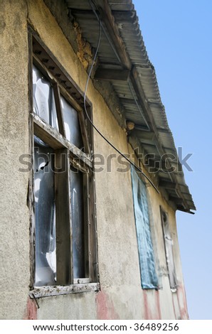 Ghetto shanty with windows punched out and replaced by plastic against sky