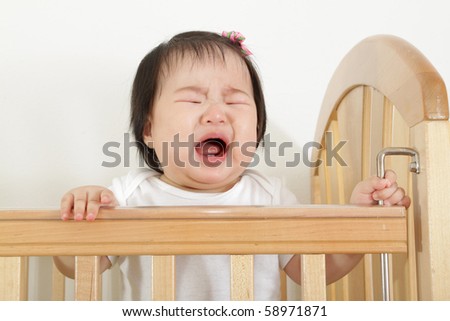 nine month old asian baby infant girl crying and bawling in wooden crib