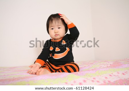 Cute Pretty Eleven Month Old Asian Infant Baby Girl Wearing Orange and Black Jack-o-lantern Pajamas