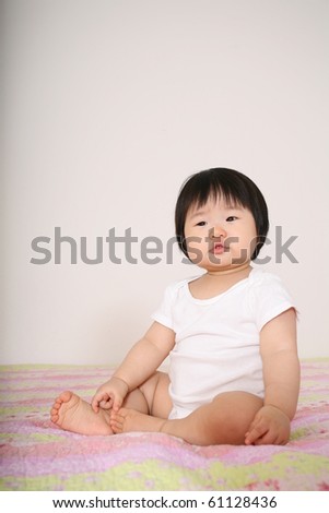 Cute Pretty Eleven Month Old Asian Infant Baby Girl Dressed in White Bodysuit with Quizzical Look on Face