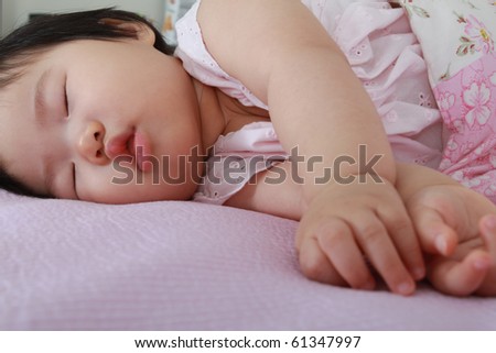 Beautiful ten month old asian baby infant girl in pink and white bodysuit fast asleep