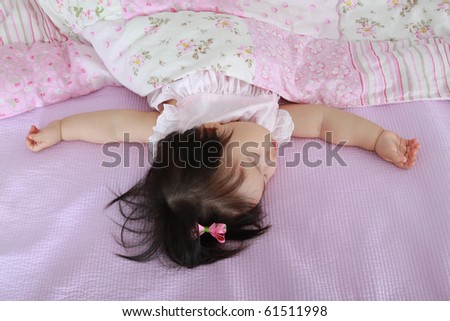 Beautiful ten month old asian baby infant girl sleeping soundly on pink bed spread