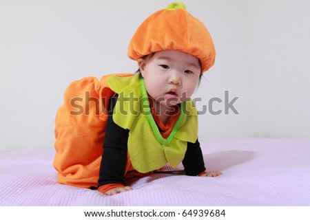 Beautiful Eleven Month Old Baby Infant East Asian Girl in Orange Jack O Lantern Pumkin Outfit Sitting on Bed Getting Ready to Trick or Treat