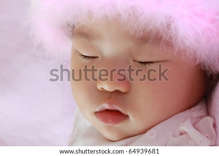Beautiful Eleven Month Old Baby Infant East Asian Girl Sleeping with Head Covered by Pink Furry Hat
