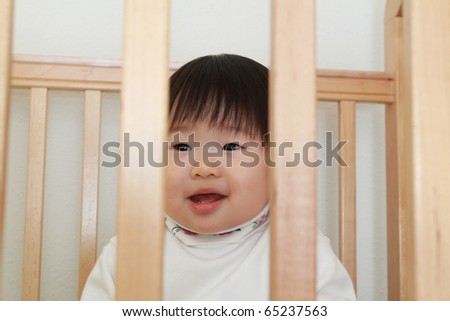 Beautiful One Year Old Baby East Asian Infant Girl Smiling Widely Inside Wooden Crib