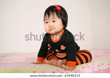 Beautiful Eleven Month Old Baby Asian Infant Girl Smiling in Jack O Lantern Shirt and Pajamas