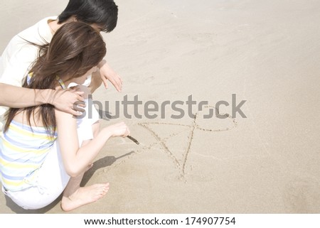 Japanese Couple drawing love on the beach