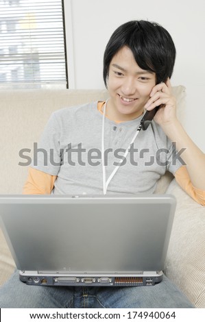 Japanese Man having a conversation on the mobile phone while looking at the computer