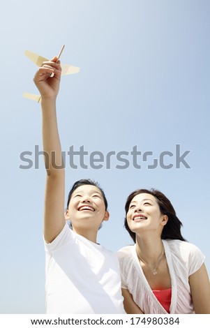 Japanese Mother looking at girls who are trying to fly paper airplane