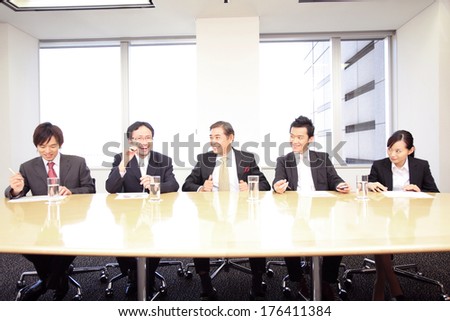 Japanese Businessmen sitting side by side at a conference table