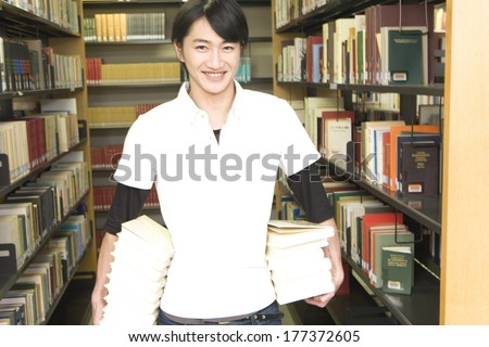 Japanese student with a stack of books in library