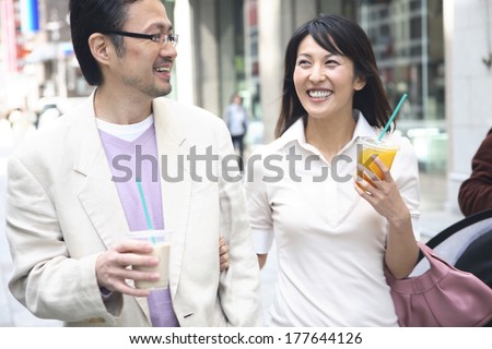 Middle Japanese couple who walks in the town while drinking a drink