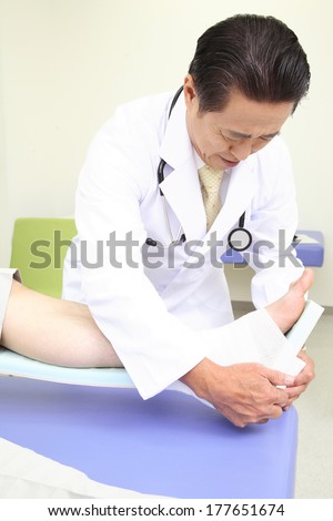 Japanese Doctor putting bandage the foot of the patient