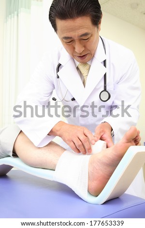 Japanese Doctor putting bandage the foot of the patient