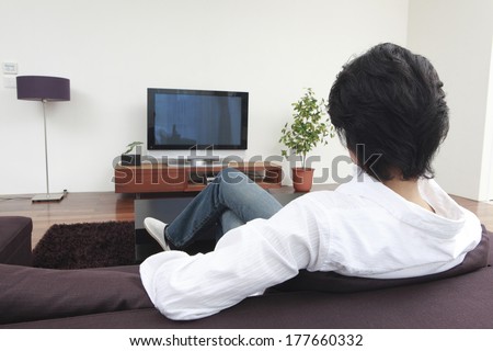 Rear View of a Japanese man watching TV in the living room