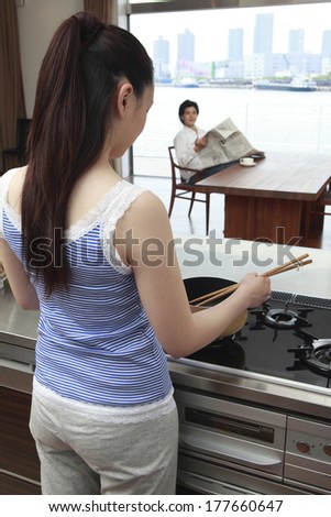 Japanese men reading a newspaper and Japanese woman cooking pasta