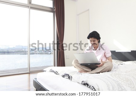 Japanese man looking at the notebook on the bed