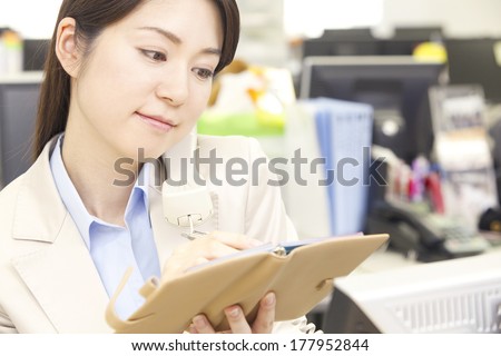 Japanese businesswoman checking the schedule while on the phone