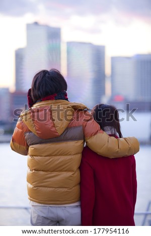 Back shot of a Japanese couple overlooking the twilight and putting arms around shoulders each other