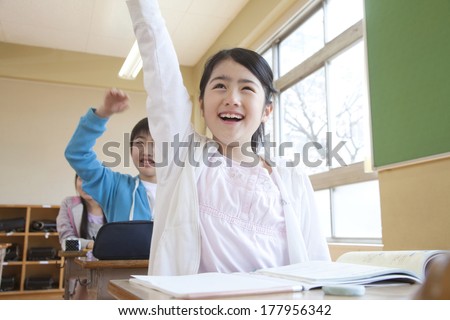 Japanese male and female elementary students raise one's hand