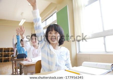 Japanese male and female elementary students raise their hands