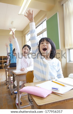 The male and female elementary students raise one\'s hand