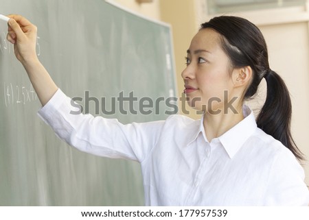 Japanese Female teacher writes a problem on the blackboard