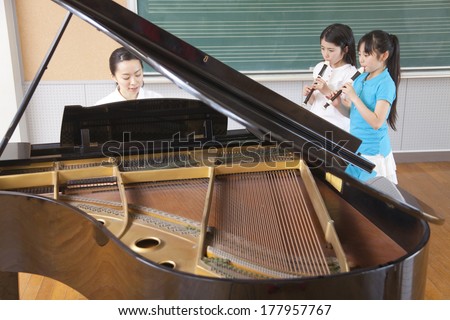 two Japanese Primary students play the recorder in a music room