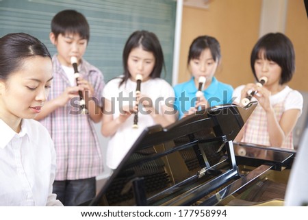 four students of Primary blow the recorder in the music room