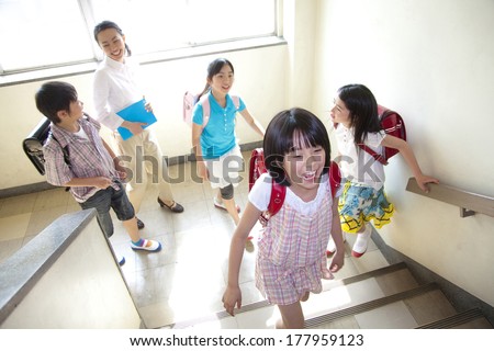 Female Japanese teachers and four elementary students going up the stairs