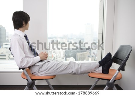Japanese Businessman taking a break putting feet on the chair