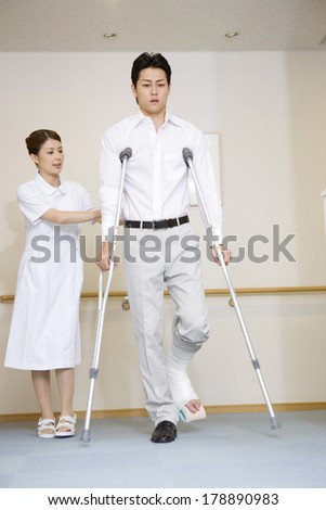 Japanese Nurse walking together with a patient with crutches