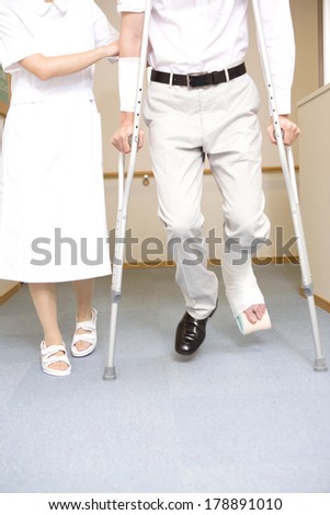 Nurse walking together with a patient with crutches