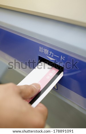 The hand of Japanese man to insert the consultation card into the card writer