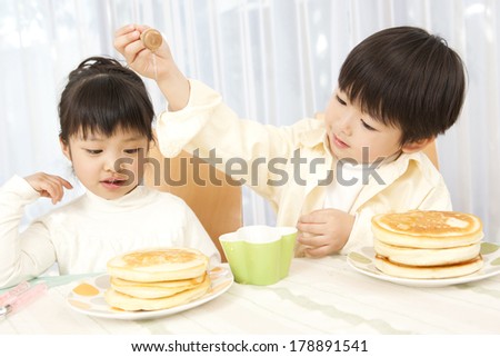 Japanese boy smearing honey on pancakes