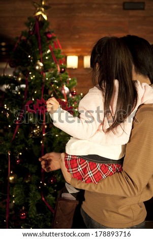 Back of Japanese father and daughter decorating the Christmas tree