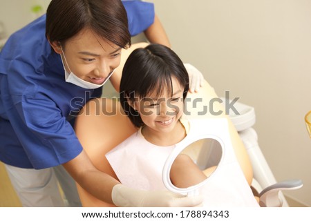 male dentist and a Japanese woman in the mirror after treatment