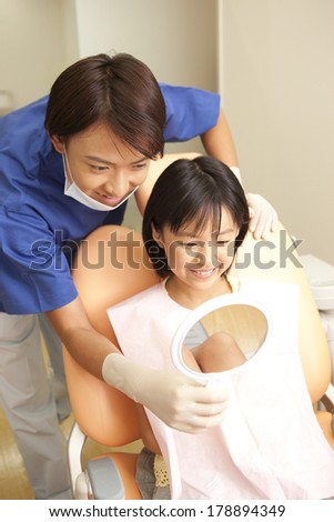 male dentist and a Japanese woman in the mirror after treatment