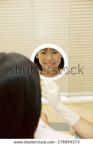Japanese girl looking at herself in a mirror after the treatment