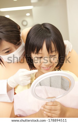 Japanese woman dentist and little girl looking in the mirror