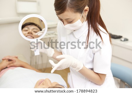 Male Japanese patient and dental hygienist looking into the treatment on the hand mirror