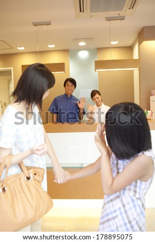 Japanese Parent and child who are going to leave the dentist and the dental staff who wave their hand