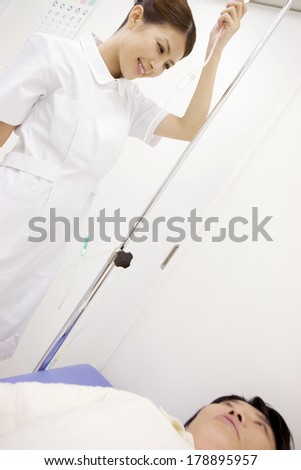 Japanese Nurse preparing intravenous injection for patients lying in bed