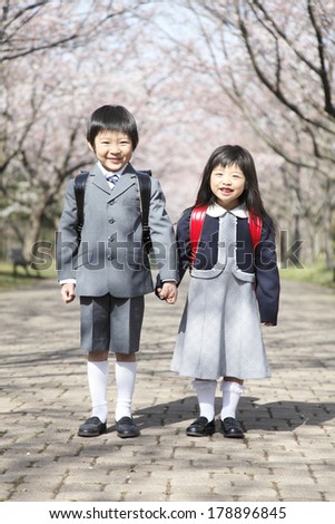Primary Japanese boy and Japanese girl standing under the cherry trees