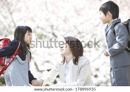 Japanese mother and elementary Japanese boy and Japanese girl talking under the cherry trees