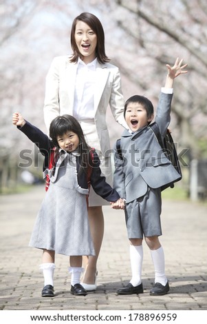 Japanese mother and elementary Japanese boy and Japanese girl to take the guts pose under the cherry trees