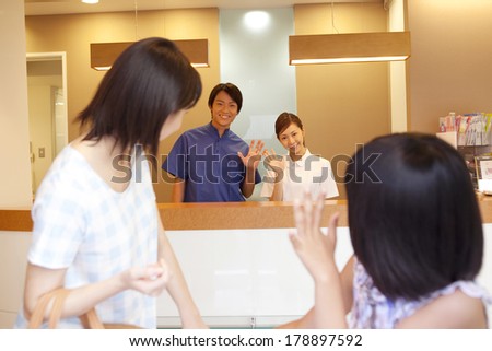 Parent and child who are going to leave the dentist and the dental staff who wave their hand