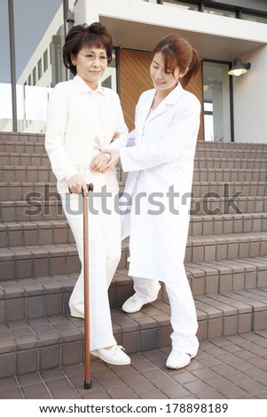 Japanese nurse helping an elderly woman walk with walking stick