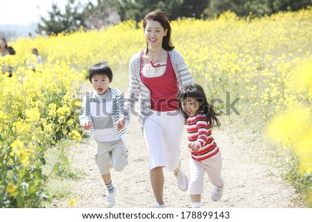Japanese mother and children running in a rapeseed field